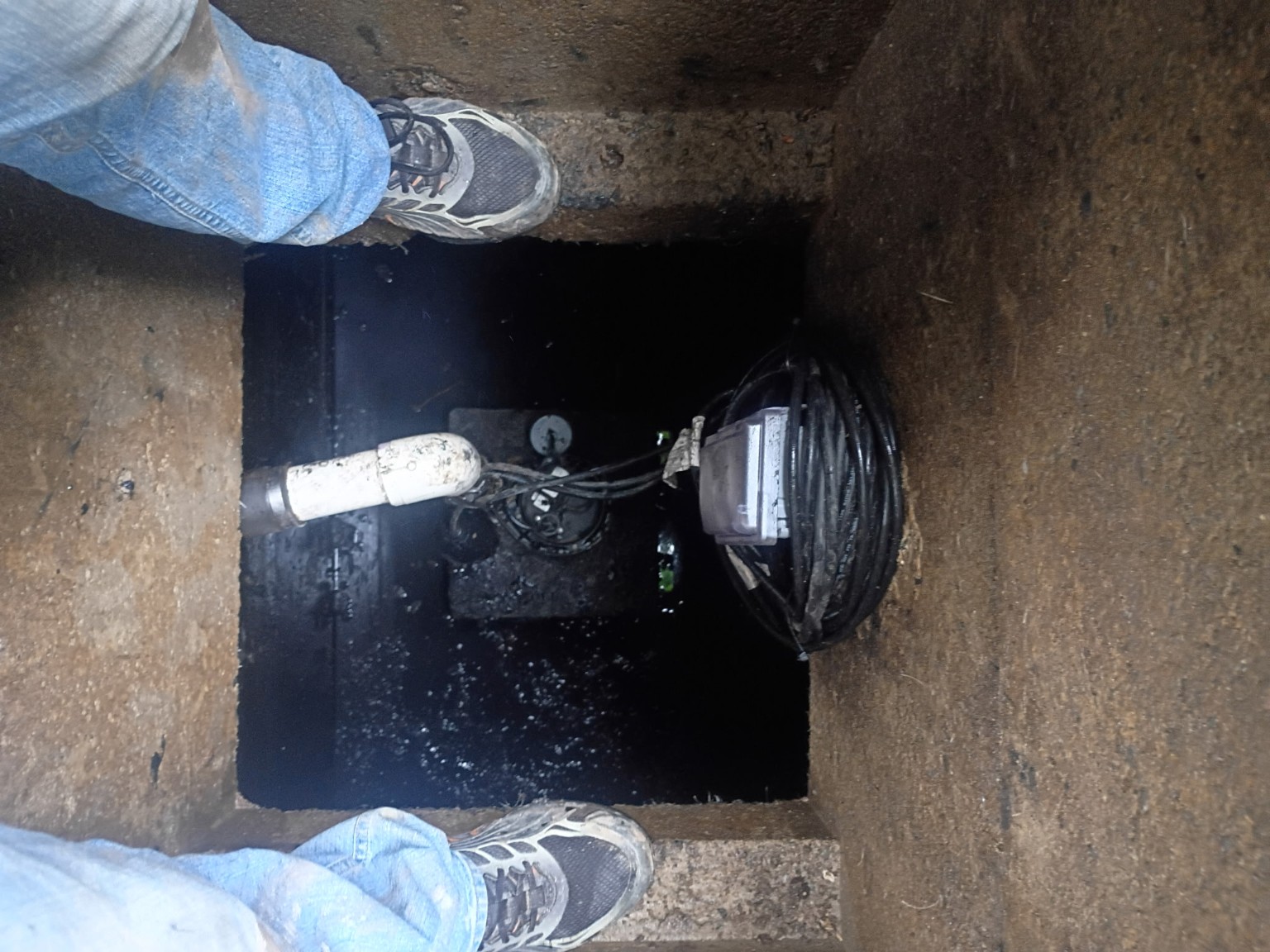 Open pump chamber showing the existing pump, discharge piping and wiring before removal